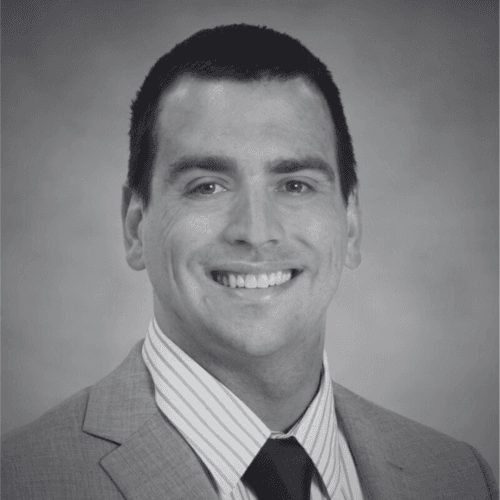 Black and white professional headshot of Clay Dorenkamp, a SovDoc leadership team member, wearing a suit and tie with a neutral background.