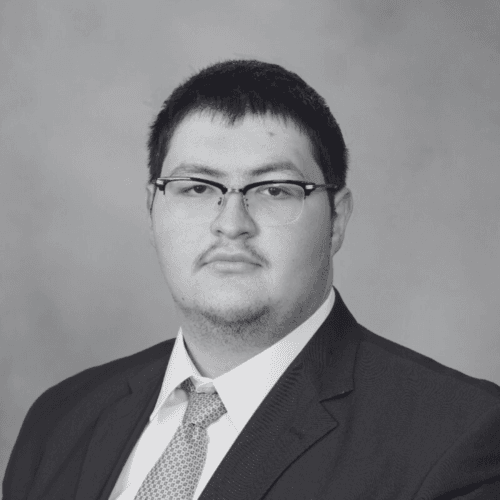 Black and white professional headshot of Tarek Arabi, a SovDoc leadership team member, wearing glasses, a suit, and a tie against a neutral background.