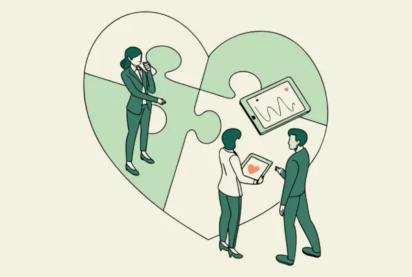 Healthcare consultants discussing cardiology practice mergers and acquisitions around a symbolic heart, representing SovDoc's specialized advisory services for medical practice M&A in the cardiovascular sector.